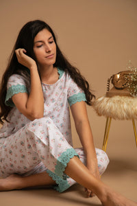 Relaxing model wearing floral Olivia Pyjama Suit with lace trim.