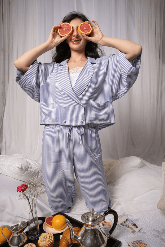 Model wearing Ono Pyjama Suit with grapefruit, stylish loungewear, cozy home setting.