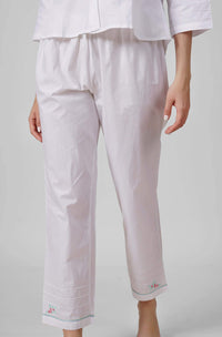 Nora pyjama suit featuring elegant white fabric and floral embroidery.