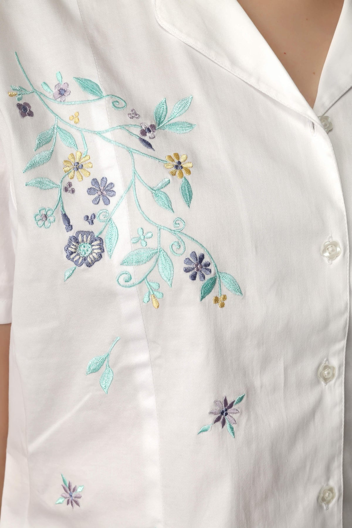 Embroidered floral design on white top for stylish summer outfit.