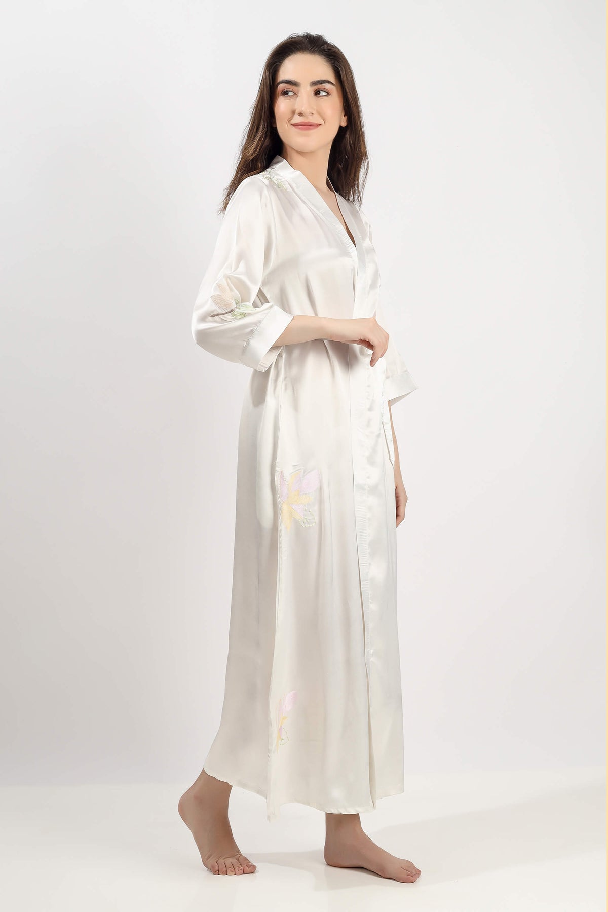 Elegant woman in embroidered gown with floral design, soft silk fabric.