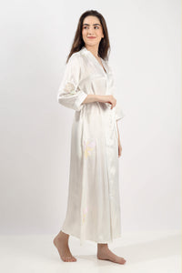 Elegant woman in embroidered gown with floral design, soft silk fabric.
