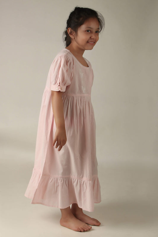 Girl wearing a pink Princess Sally nightdress, smiling happily.