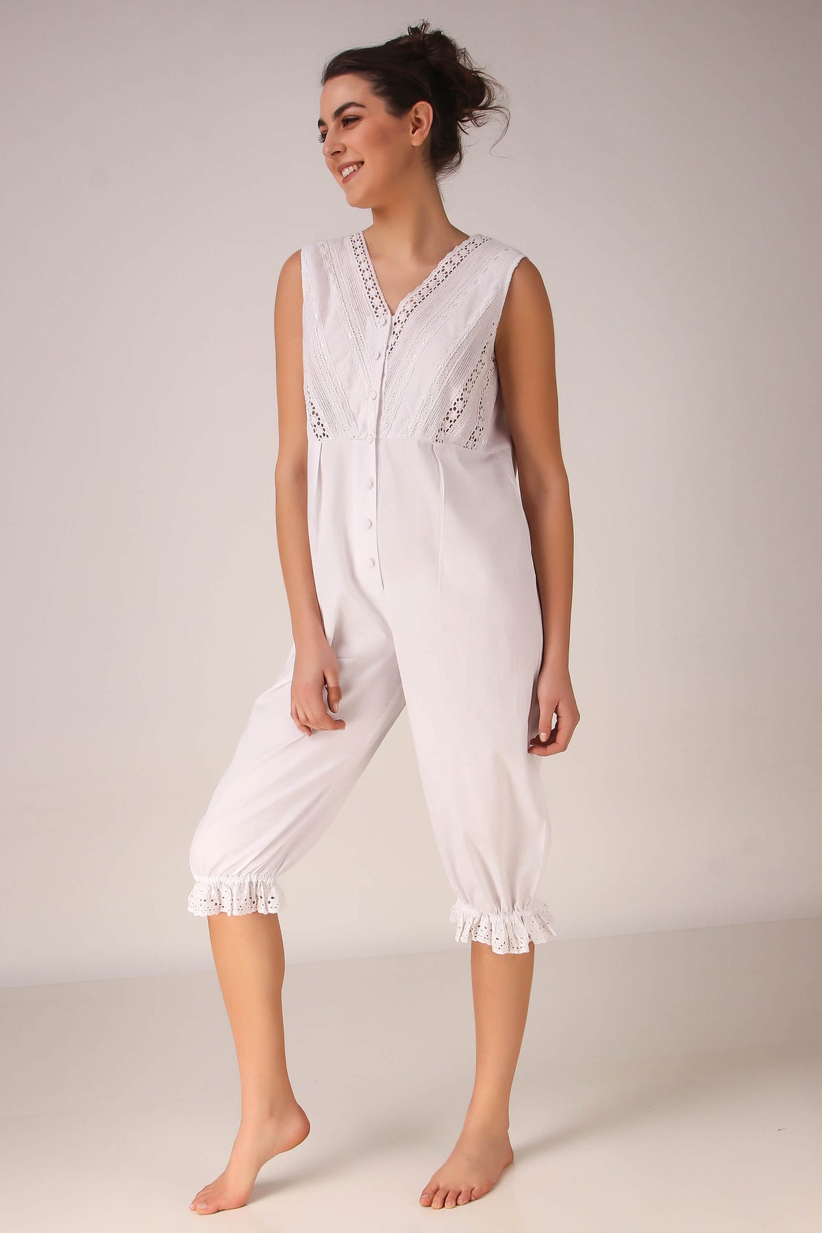 Stylish white Enola romper with lace detailing and button closure.