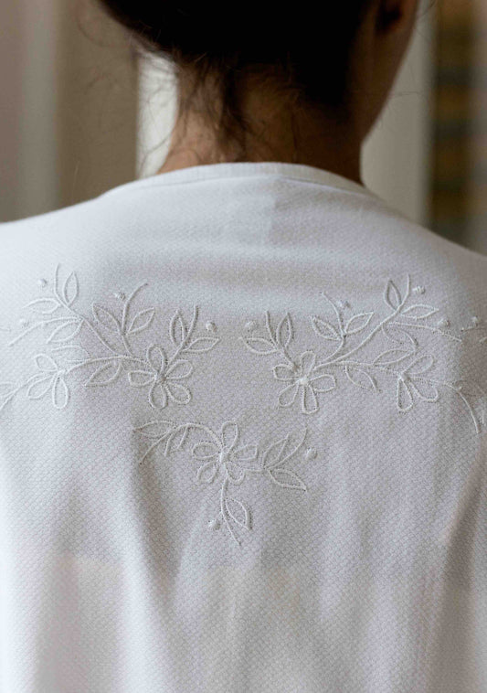Back view of feminine white nightgown with floral embroidery.